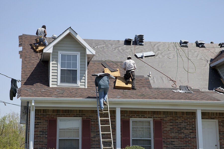 Home undergoing repairs, featuring contractors working on the roof and exterior, highlighting the challenges of selling a property that needs improvements. Home undergoing repairs, featuring contractors working on the roof and exterior, highlighting the challenges of selling a property that needs improvements.